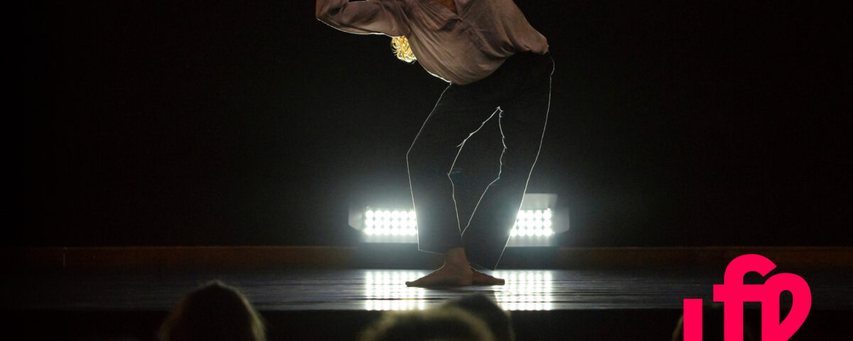 danzatrice esegue un passo di danza su un palco con luce soffusa